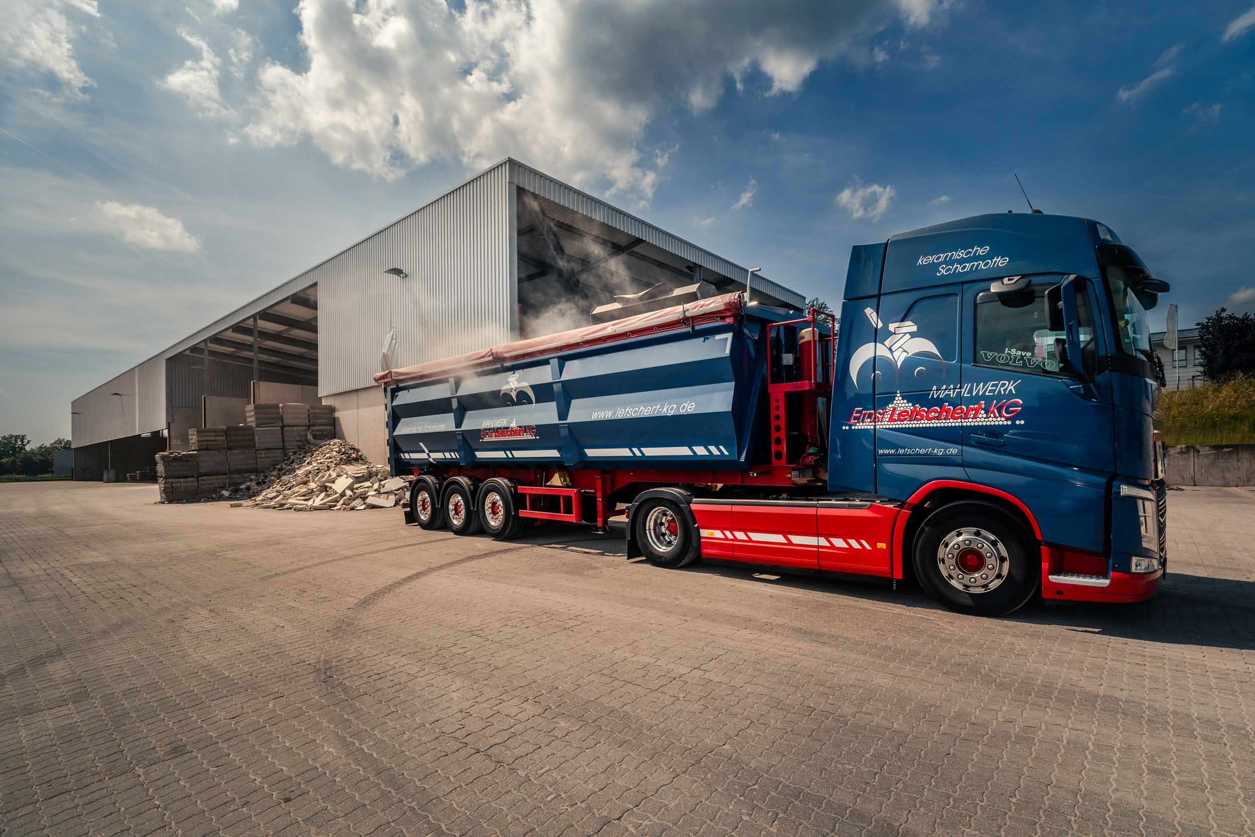 Industriefotografie: Ein LKW mit Mulde steht vor einem Gebäude mit Lagerboxen