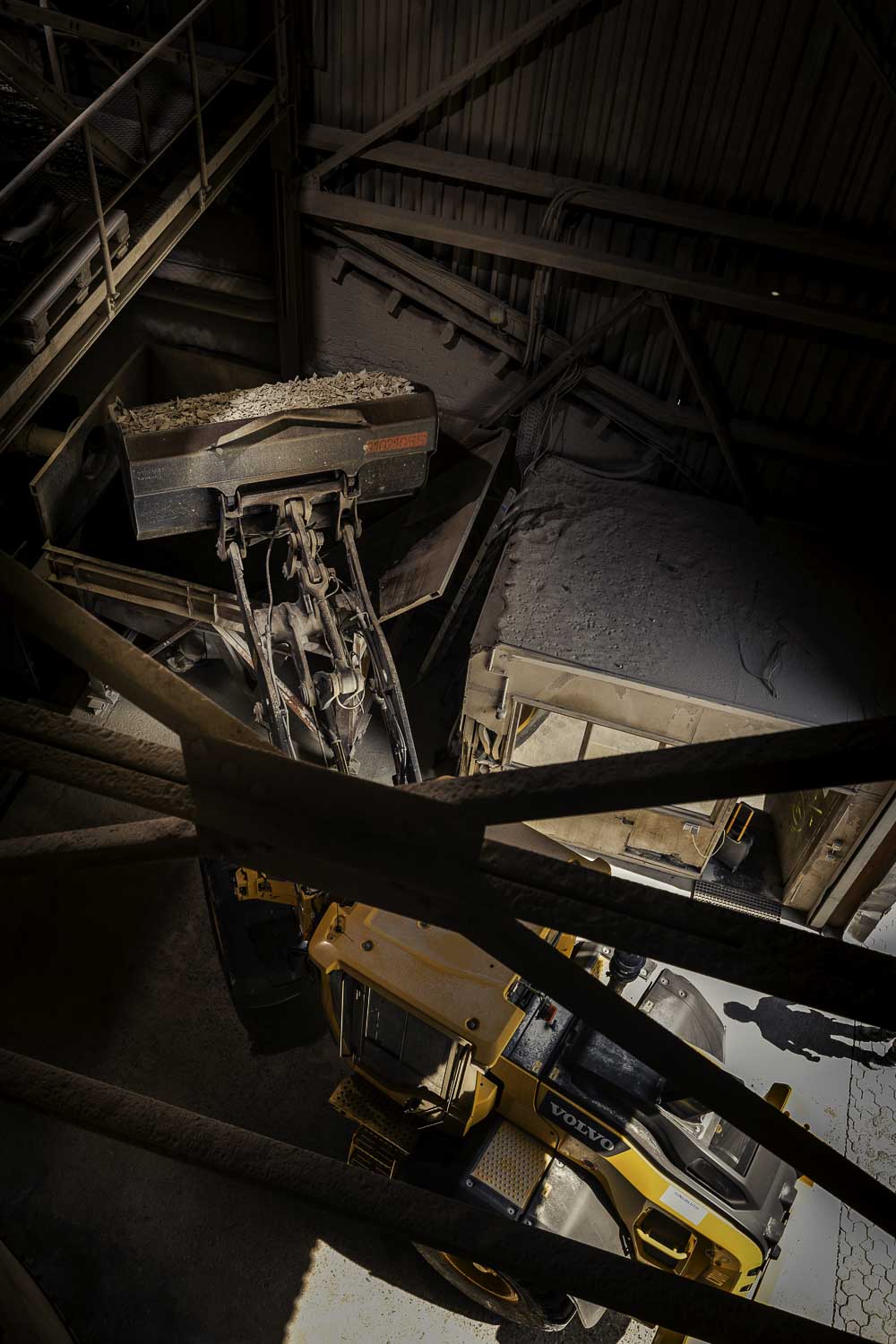 Industriefotografie: Ein Radlader befüllt die Brechanlage mit Rohmaterial aus der Keramik - eine Perspektive von oben.